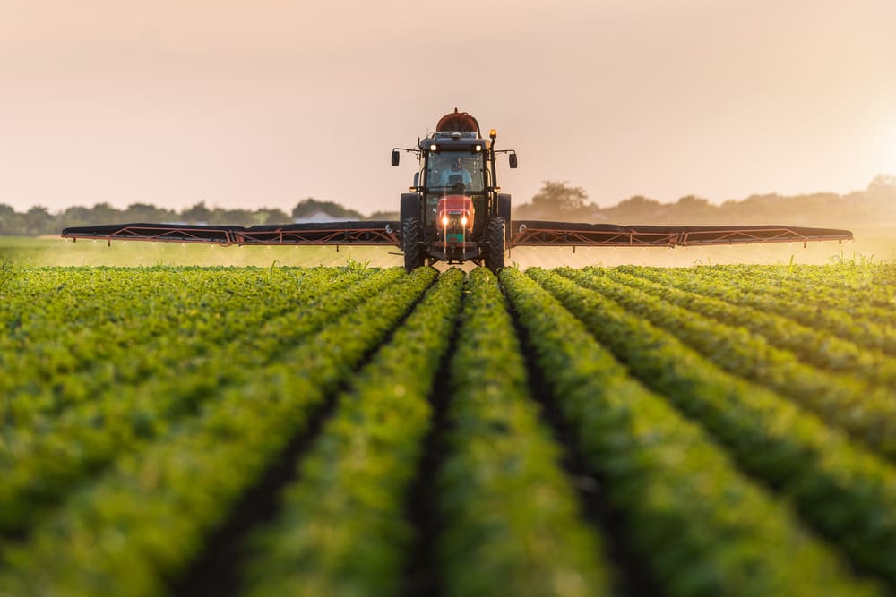 Tractor spraying pesticides on soybean field with sprayer at spring.